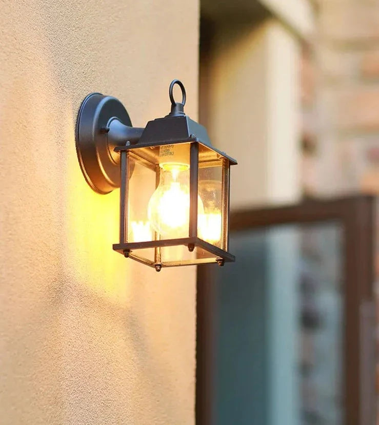 Arandela externa preta estilo lanterna retrô instalada em fachada de casa com luz amarela